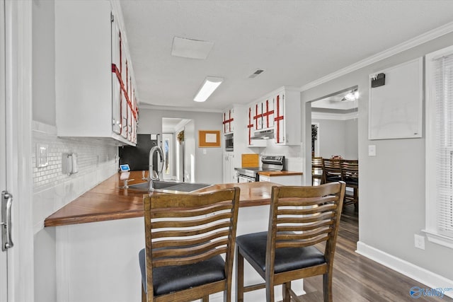 kitchen with sink, dark wood-type flooring, stainless steel appliances, crown molding, and decorative backsplash