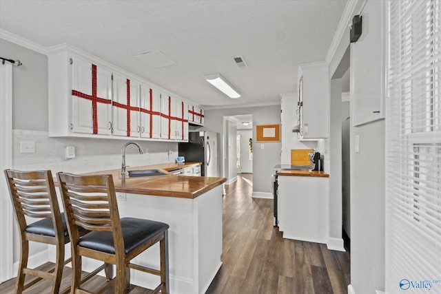 kitchen with wood counters, kitchen peninsula, dark hardwood / wood-style floors, and sink