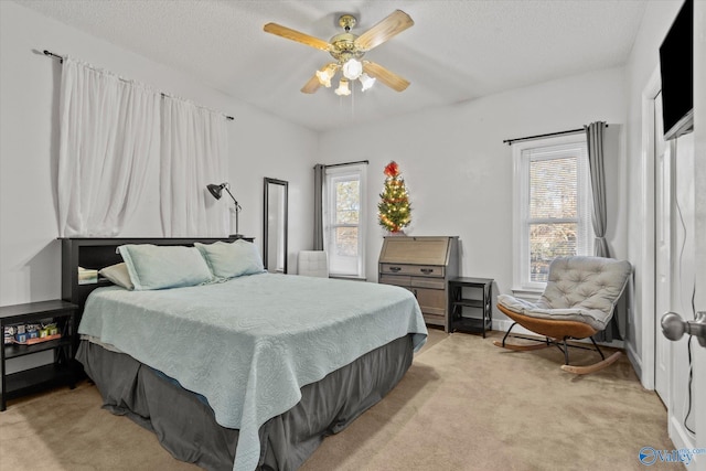 bedroom featuring a textured ceiling, light colored carpet, and ceiling fan