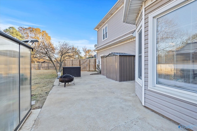 view of patio / terrace featuring a fire pit, a storage unit, an outbuilding, and a fenced backyard