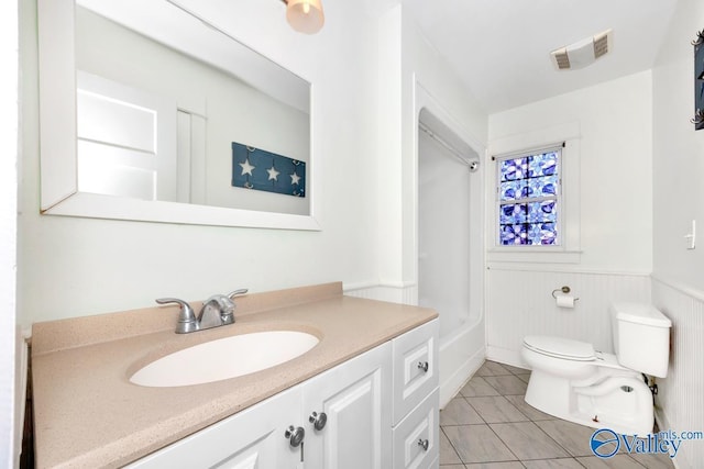 full bath with a wainscoted wall, visible vents, toilet, vanity, and tile patterned flooring