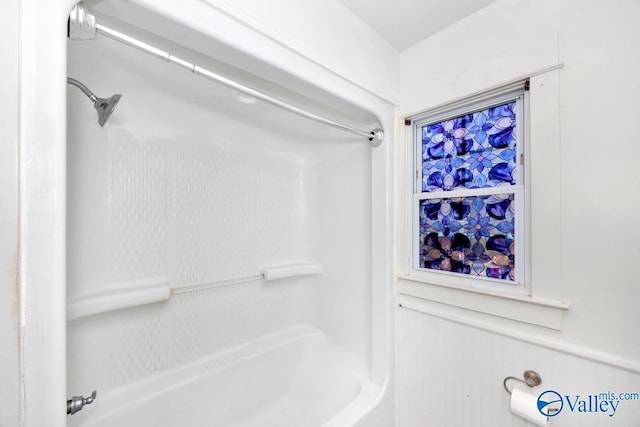 interior space featuring a wainscoted wall and shower / tub combination