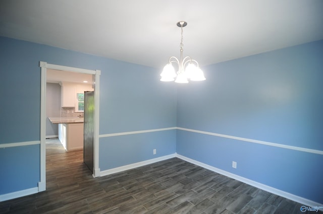 unfurnished room with dark hardwood / wood-style floors and a notable chandelier