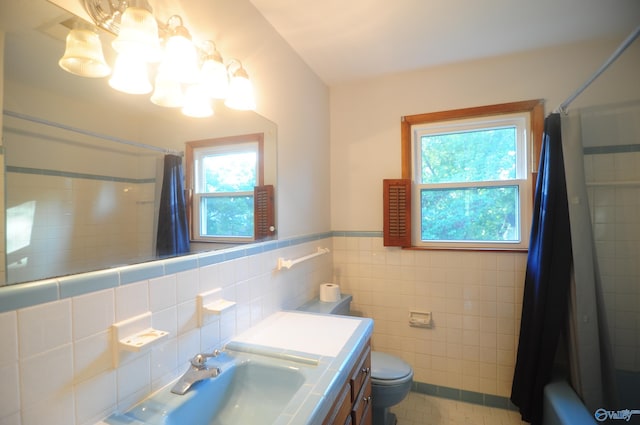 full bathroom featuring toilet, vanity, backsplash, shower / bathtub combination with curtain, and tile walls