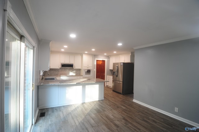 kitchen with dark hardwood / wood-style flooring, kitchen peninsula, light stone countertops, appliances with stainless steel finishes, and white cabinets