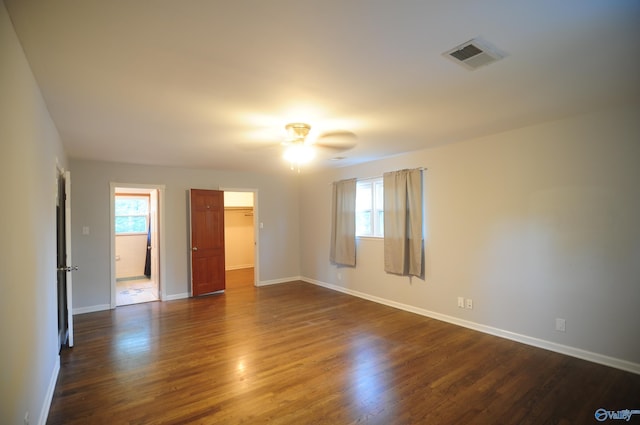 empty room with dark wood-type flooring, a wealth of natural light, and ceiling fan