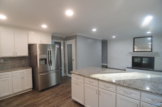 kitchen with dark hardwood / wood-style flooring, a fireplace, stainless steel refrigerator with ice dispenser, white cabinetry, and light stone counters