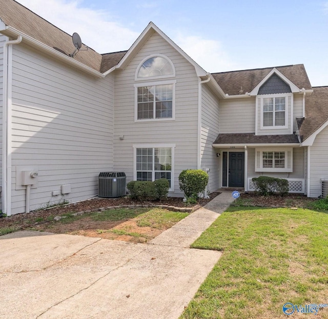 traditional home with central air condition unit and a front lawn