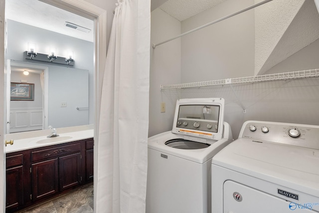 clothes washing area with washing machine and dryer, sink, and a textured ceiling