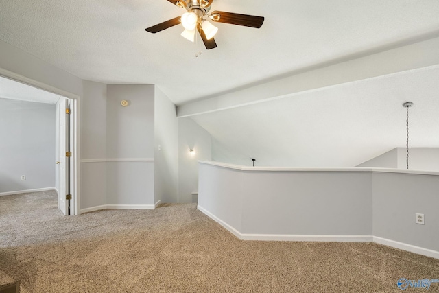 carpeted spare room with lofted ceiling with beams, ceiling fan, baseboards, and a textured ceiling