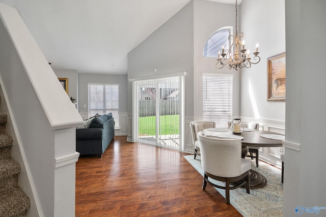 dining space with high vaulted ceiling, a wainscoted wall, stairway, dark wood finished floors, and an inviting chandelier