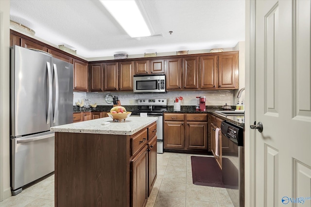 12100 Two Rivers Dr Phi, Phi, Athens, AL 35611 - kitchen featuring stainless steel appliances, light tile patterned floors, tasteful backsplash, a kitchen island, and dark stone countertops