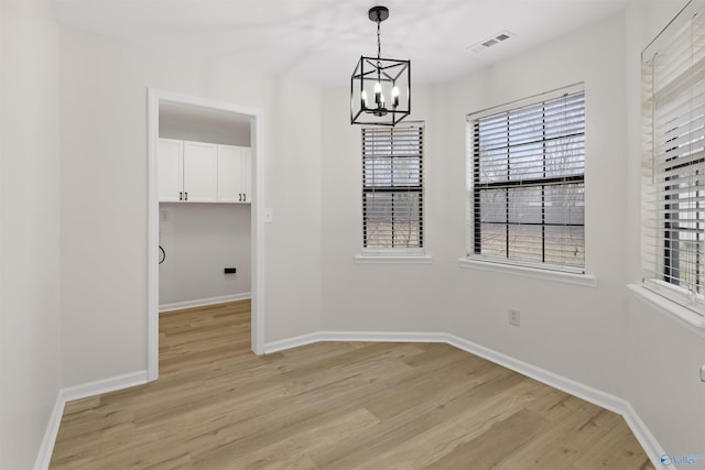 unfurnished dining area with light hardwood / wood-style floors and a chandelier