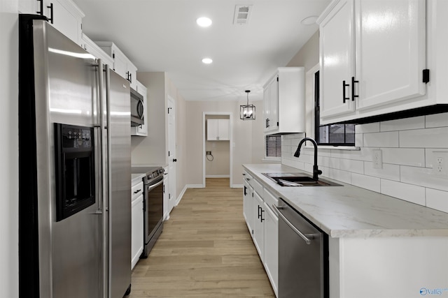 kitchen featuring appliances with stainless steel finishes, sink, pendant lighting, and white cabinets