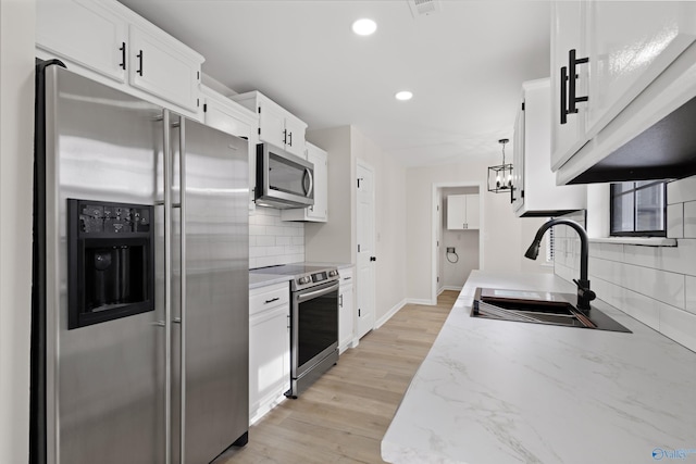 kitchen with light hardwood / wood-style flooring, sink, white cabinetry, pendant lighting, and stainless steel appliances