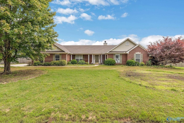 ranch-style house featuring brick siding, a chimney, a front yard, and fence