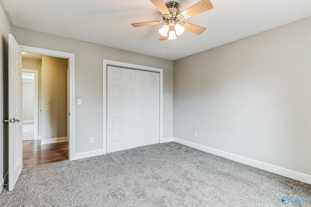 unfurnished bedroom with a textured ceiling, carpet, ceiling fan, and a closet