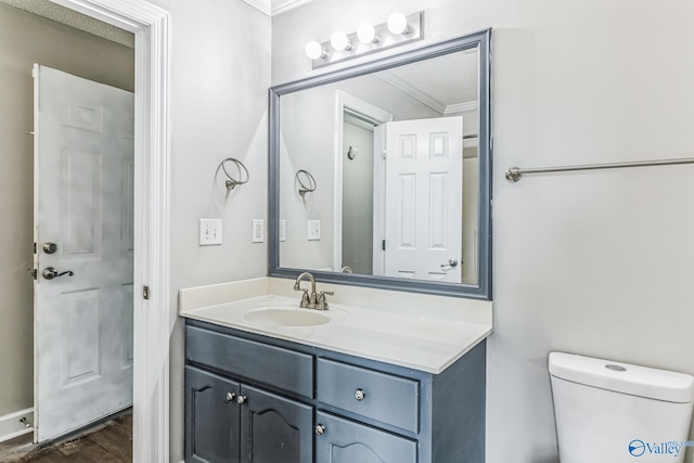 bathroom with ornamental molding, toilet, vanity, and hardwood / wood-style floors