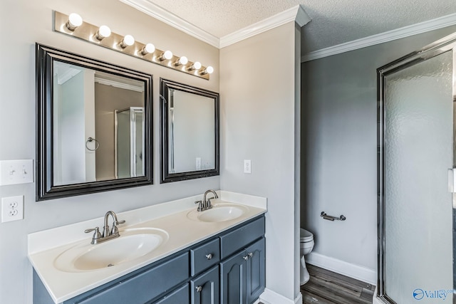 bathroom featuring crown molding, a textured ceiling, toilet, dual vanity, and hardwood / wood-style floors