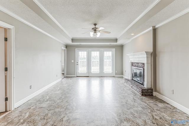 unfurnished living room featuring tile patterned flooring, crown molding, a brick fireplace, ceiling fan, and a raised ceiling