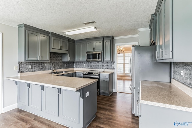 kitchen with appliances with stainless steel finishes, sink, kitchen peninsula, dark hardwood / wood-style floors, and ornamental molding