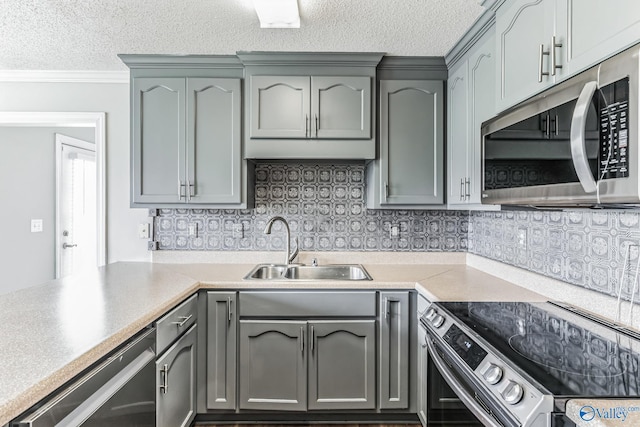 kitchen with crown molding, light countertops, appliances with stainless steel finishes, a sink, and a textured ceiling