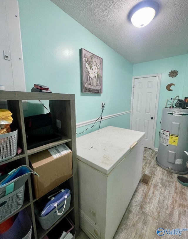1055 Georgia Mountain Rd, Guntersville, AL 35976 - laundry room featuring electric water heater, light wood-style flooring, and a textured ceiling