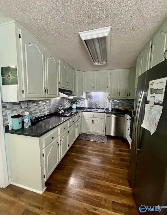 1055 Georgia Mountain Rd, Guntersville, AL 35976 - kitchen with appliances with stainless steel finishes, dark countertops, under cabinet range hood, a sink, and dark wood finished floors