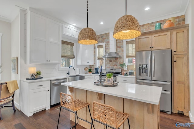 kitchen featuring wall chimney exhaust hood, sink, decorative light fixtures, a center island, and stainless steel appliances