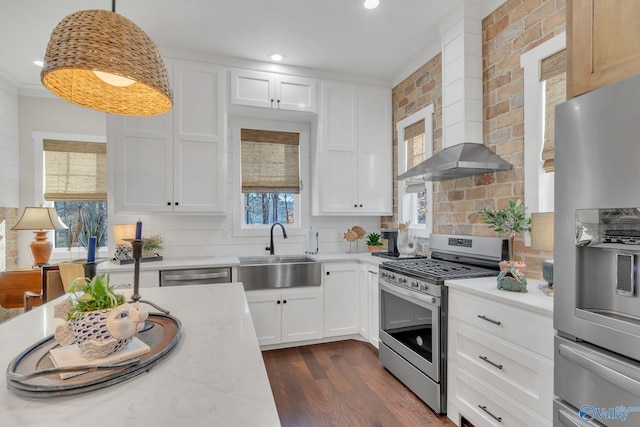 kitchen featuring white cabinetry, sink, hanging light fixtures, stainless steel appliances, and light stone countertops