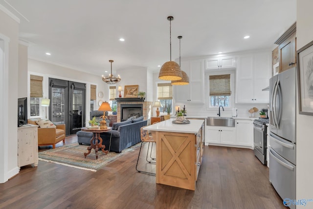 kitchen with decorative light fixtures, sink, white cabinets, a center island, and stainless steel appliances