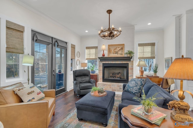 living room with crown molding, wood-type flooring, a fireplace, and a chandelier