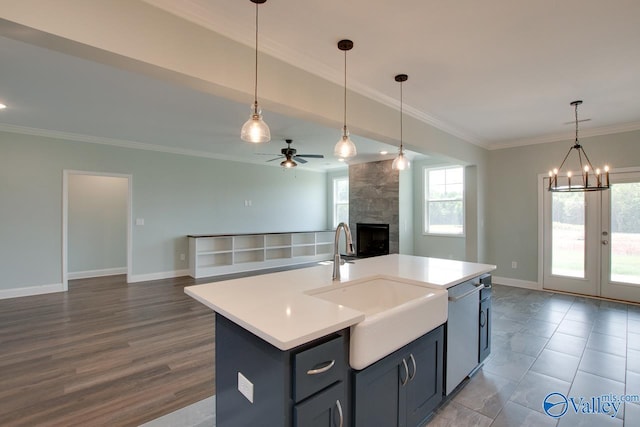 kitchen featuring pendant lighting, ceiling fan with notable chandelier, wood-type flooring, and a kitchen island with sink