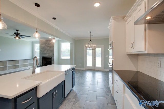 kitchen featuring stainless steel appliances, blue cabinets, pendant lighting, extractor fan, and white cabinets