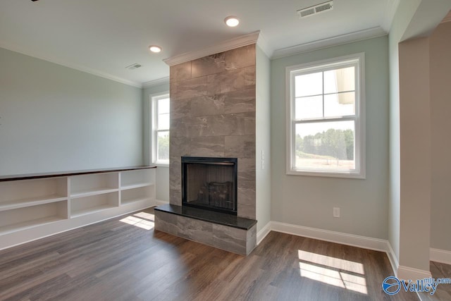 unfurnished living room with a tile fireplace, plenty of natural light, dark hardwood / wood-style floors, and ornamental molding