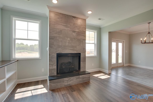 unfurnished living room with hardwood / wood-style floors, a tiled fireplace, crown molding, and french doors