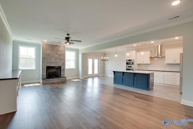 kitchen featuring blue cabinetry, hanging light fixtures, white cabinets, and light hardwood / wood-style floors