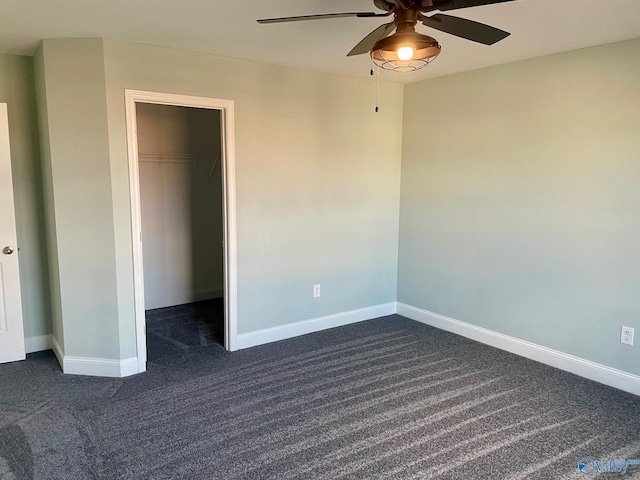 unfurnished bedroom featuring dark colored carpet, ceiling fan, a walk in closet, and a closet