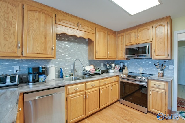 kitchen featuring decorative backsplash, stainless steel appliances, sink, and light hardwood / wood-style flooring