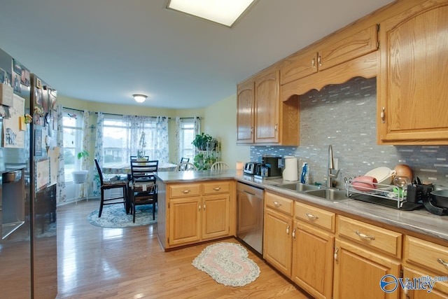 kitchen featuring tasteful backsplash, stainless steel dishwasher, sink, and light hardwood / wood-style floors