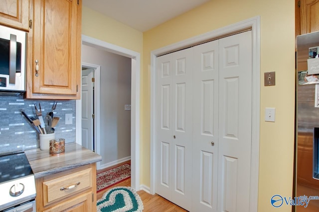 kitchen featuring light hardwood / wood-style flooring, range, light brown cabinetry, and backsplash