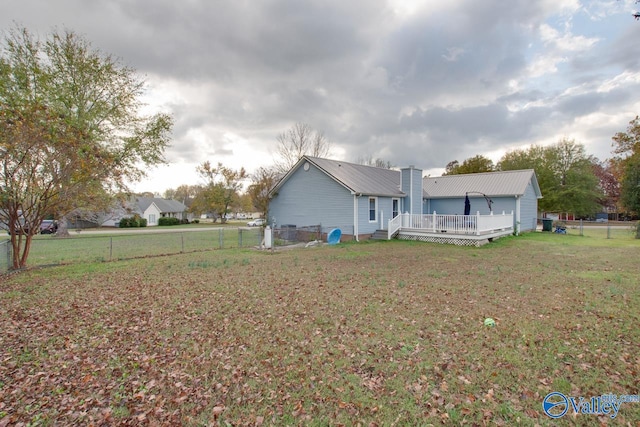 rear view of house featuring a wooden deck and a lawn