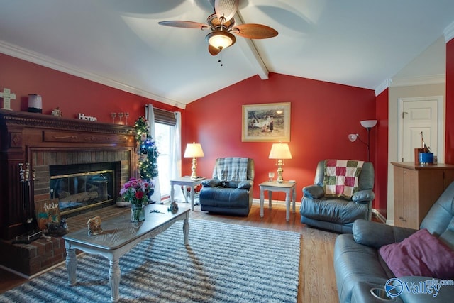 living room featuring a brick fireplace, vaulted ceiling with beams, hardwood / wood-style floors, ornamental molding, and ceiling fan