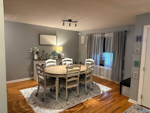 dining room with wood-type flooring and a textured ceiling