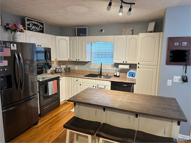 kitchen with butcher block counters, sink, white cabinets, and black appliances