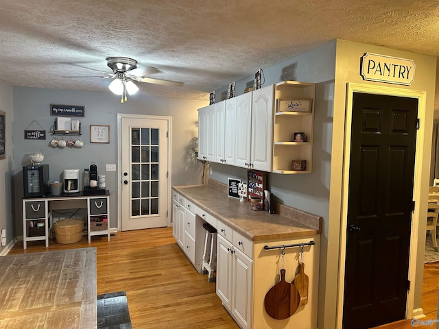 kitchen featuring ceiling fan, a textured ceiling, light hardwood / wood-style flooring, and white cabinets