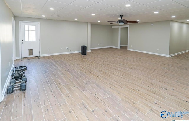 basement featuring a paneled ceiling, ceiling fan, and light wood-type flooring