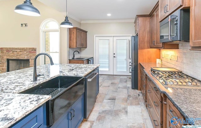 kitchen featuring light tile patterned flooring, hanging light fixtures, ornamental molding, appliances with stainless steel finishes, and backsplash