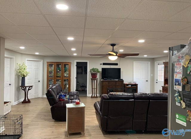 living room with ceiling fan, light hardwood / wood-style flooring, and a drop ceiling