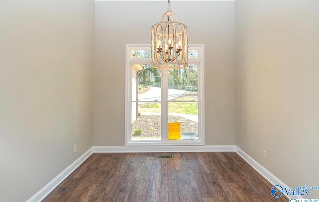 unfurnished dining area with dark wood-type flooring and an inviting chandelier